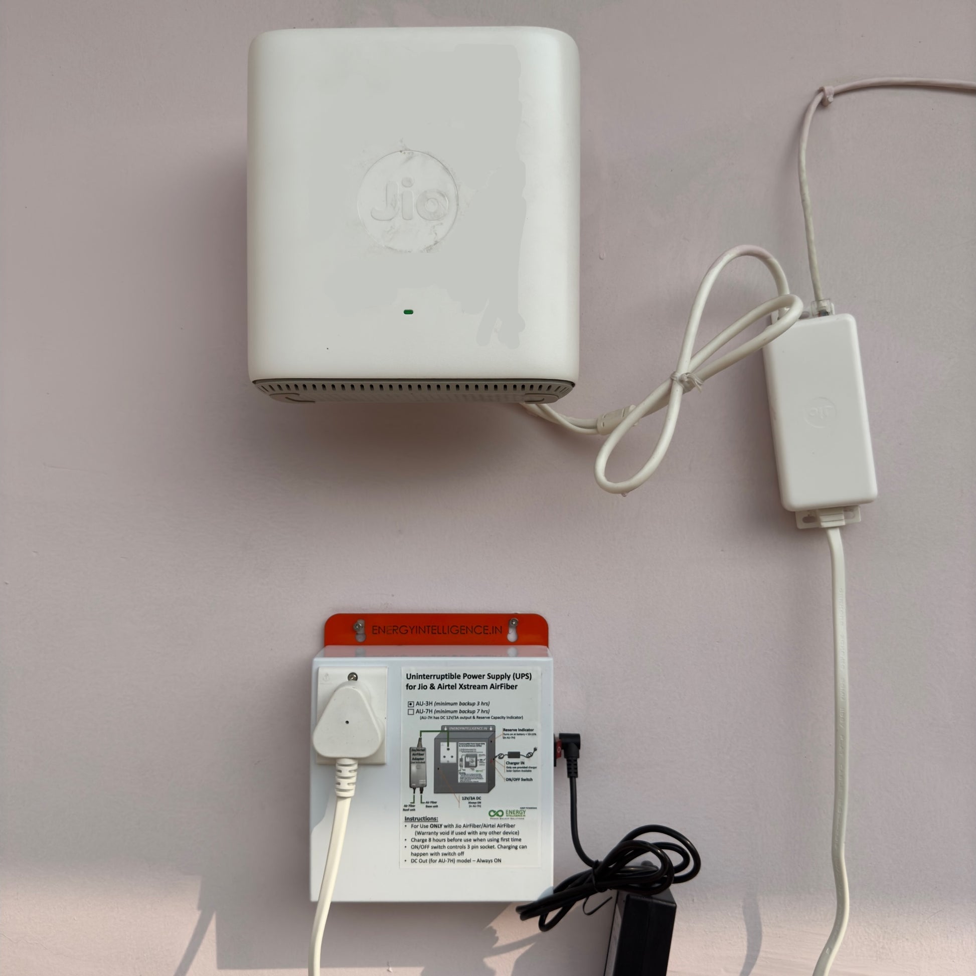 AU3H - Airfiber UPS for Jio AirFiber and Airtel Airfiber mounted on the wall next to a Jio AirFiber unit